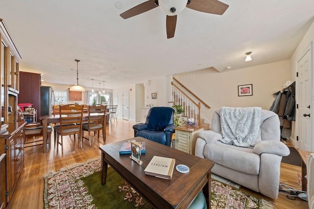 living area featuring a ceiling fan, light wood-type flooring, and stairway