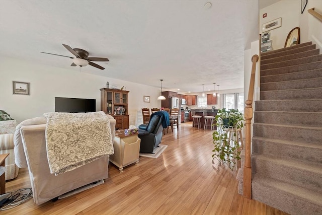 living room with light wood finished floors, stairway, and a ceiling fan