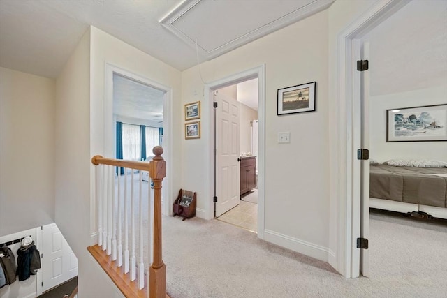 corridor with carpet, an upstairs landing, attic access, and baseboards