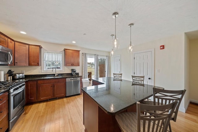 kitchen featuring stainless steel appliances, a breakfast bar, light wood-style floors, and a sink