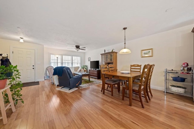 dining room featuring baseboards, a ceiling fan, and light wood-style floors