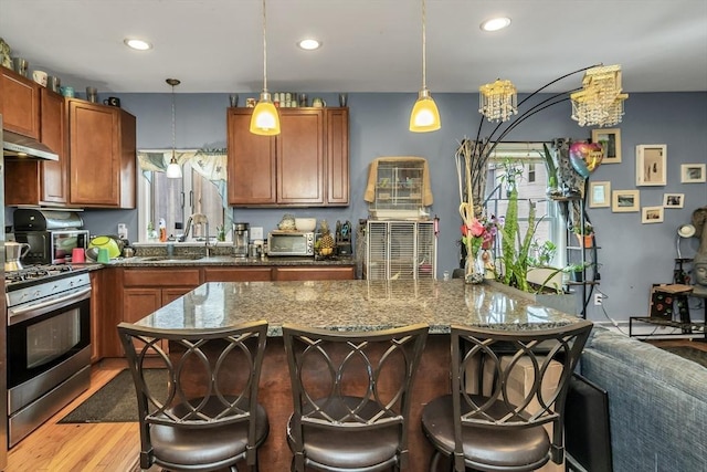 7 S Harlem St, Worcester, MA 01610 - kitchen with stainless steel range with gas stovetop, extractor fan, decorative light fixtures, a breakfast bar, and dark stone counters
