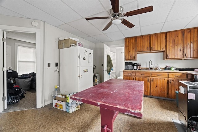 19 Park St, Webster, MA 01570 - kitchen with freestanding refrigerator, ceiling fan, brown cabinetry, a sink, and a paneled ceiling