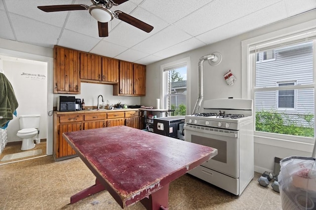 19 Park St, Webster, MA 01570 - kitchen with gas range gas stove, brown cabinets, a paneled ceiling, a sink, and baseboards