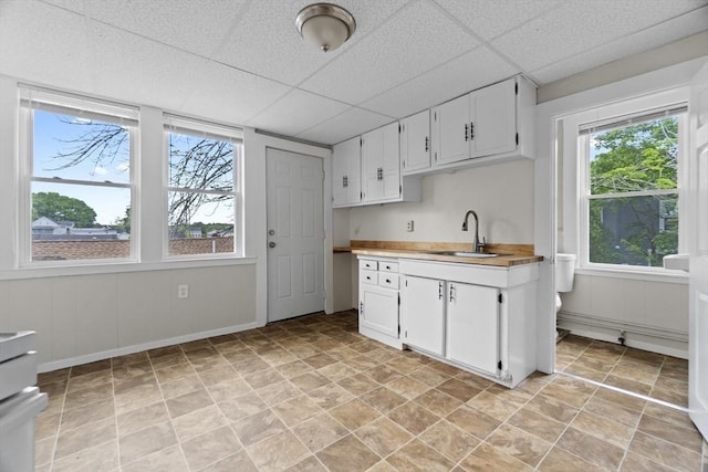 19 Park St, Webster, MA 01570 - kitchen featuring a sink, light countertops, white cabinetry, a drop ceiling, and stone finish floors