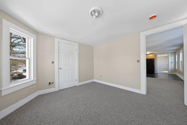 unfurnished room featuring dark colored carpet