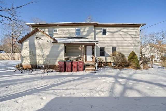 snow covered house featuring covered porch