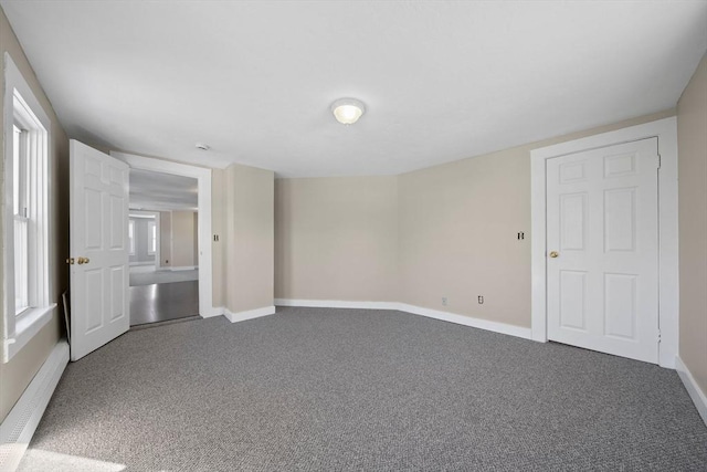 unfurnished bedroom with a baseboard heating unit and carpet