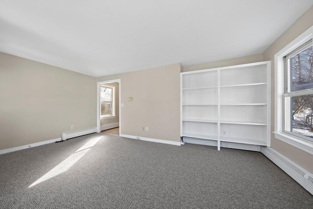 carpeted spare room featuring a baseboard heating unit and plenty of natural light