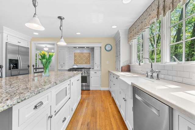 63 Claypit Hill Rd, Wayland, MA 01778 - kitchen featuring built in appliances, backsplash, white cabinetry, decorative light fixtures, and light wood-style flooring