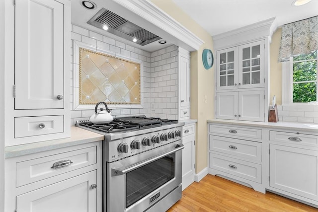 63 Claypit Hill Rd, Wayland, MA 01778 - kitchen with stainless steel stove, decorative backsplash, custom exhaust hood, light countertops, and white cabinets