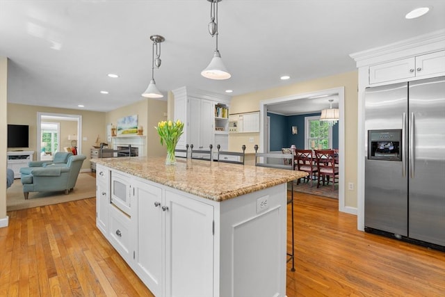 63 Claypit Hill Rd, Wayland, MA 01778 - kitchen featuring built in appliances, white cabinets, light wood-type flooring, light stone counters, and recessed lighting
