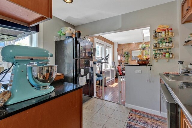 kitchen with freestanding refrigerator, light tile patterned floors, a wealth of natural light, and dark countertops