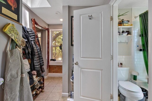 mudroom featuring baseboards, a skylight, and light tile patterned floors