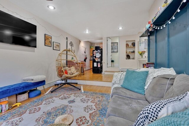 living room with built in features, recessed lighting, and wood finished floors