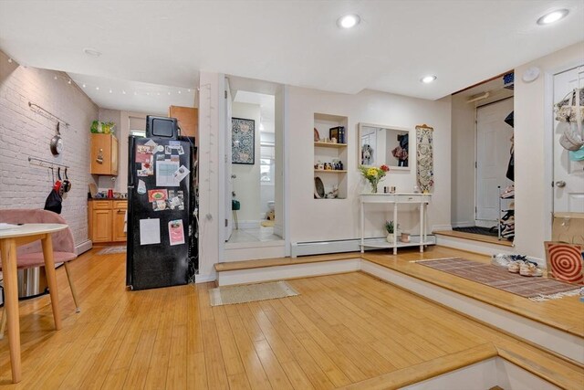 entryway featuring brick wall, baseboards, a baseboard heating unit, light wood-style floors, and recessed lighting