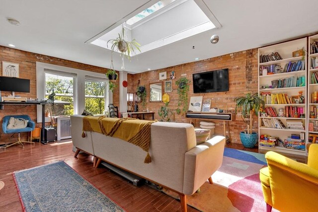 living room with wood finished floors, brick wall, and a skylight
