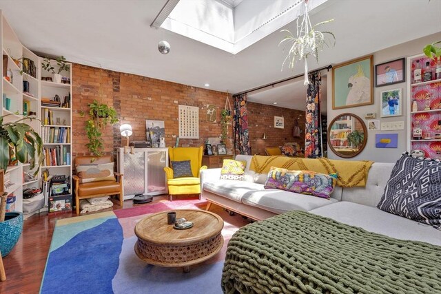 living area with a chandelier, brick wall, and wood finished floors