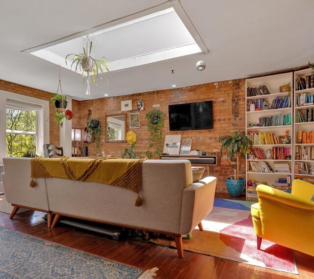 living room with a skylight, brick wall, and hardwood / wood-style floors
