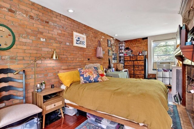 bedroom featuring wood finished floors, brick wall, and cooling unit