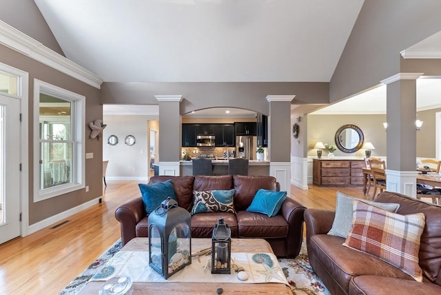living area featuring visible vents, decorative columns, vaulted ceiling, and light wood-type flooring