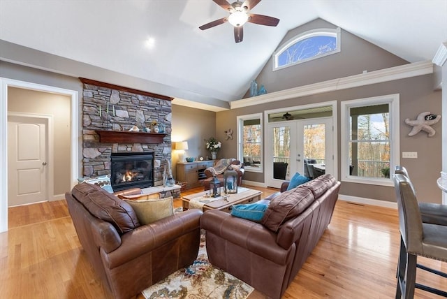 living area with french doors, a ceiling fan, a fireplace, baseboards, and light wood finished floors