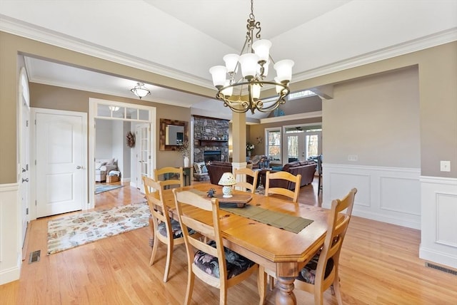 dining area with visible vents, wainscoting, an inviting chandelier, and light wood-type flooring