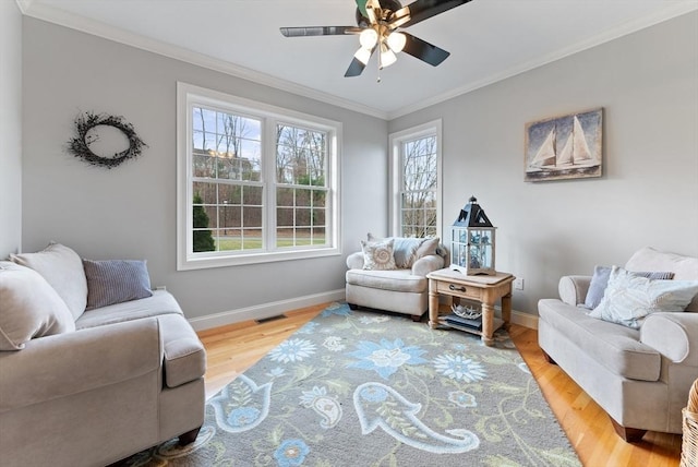 living area featuring visible vents, ornamental molding, baseboards, and ceiling fan