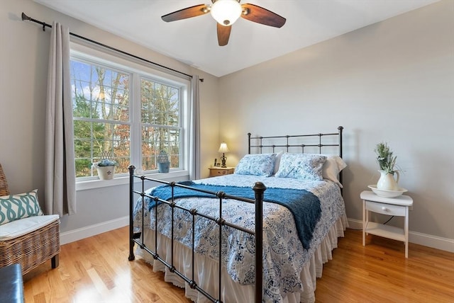 bedroom with a ceiling fan, baseboards, and wood finished floors