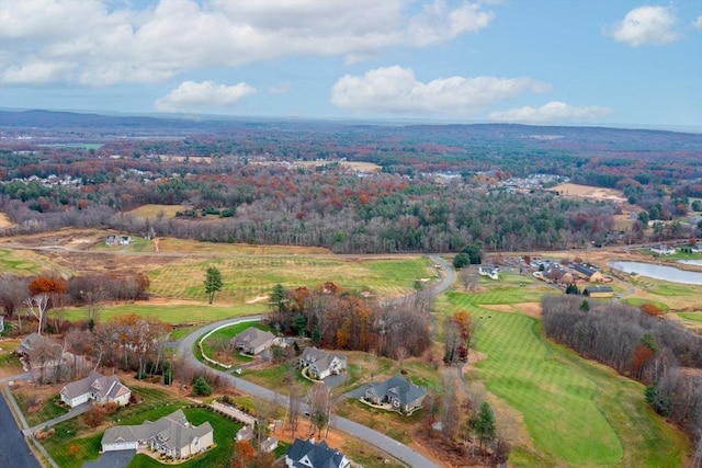 drone / aerial view featuring a water view, view of golf course, a residential view, and a wooded view