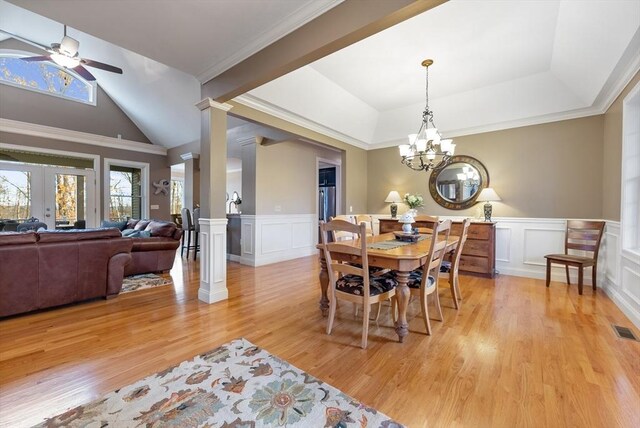 dining space with ceiling fan with notable chandelier, a decorative wall, light wood-type flooring, and visible vents