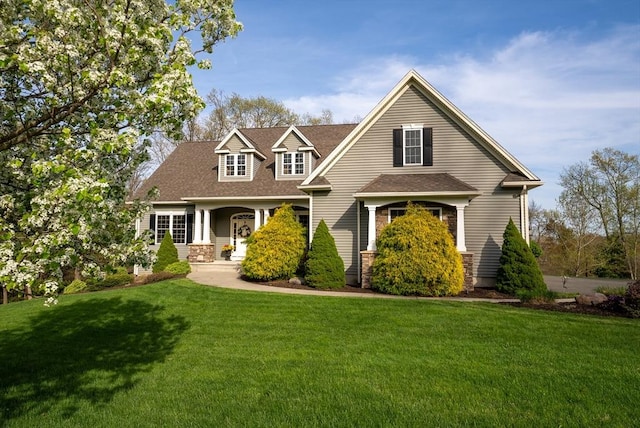 new england style home with roof with shingles and a front yard