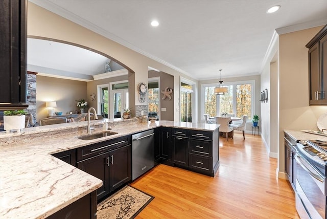 kitchen featuring appliances with stainless steel finishes, arched walkways, light stone countertops, a sink, and light wood-style flooring