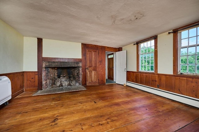 40 Whately Glen Rd, Conway, MA 01341 - unfurnished living room with a baseboard radiator, wainscoting, wood-type flooring, wood walls, and a brick fireplace