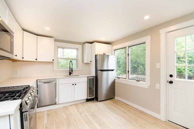 67 Thatcher St, Brockton, MA 02302 - kitchen featuring appliances with stainless steel finishes, a sink, decorative backsplash, light countertops, and light wood-style flooring