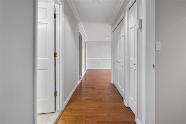 corridor with light wood-type flooring and ornamental molding