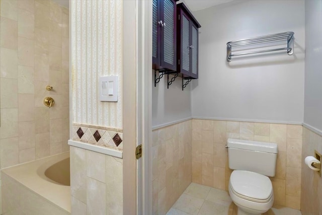 bathroom with tile walls, a bath, tile patterned floors, and toilet