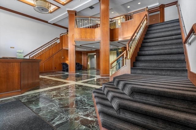 staircase with wooden walls, a towering ceiling, and beamed ceiling