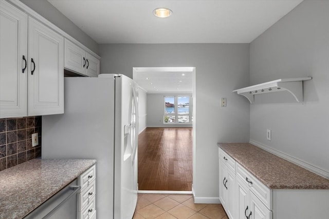 kitchen with light wood-type flooring, white fridge with ice dispenser, white cabinetry, and decorative backsplash