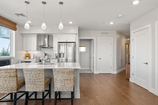 130 Broad Reach Unit 409, Weymouth, MA 02191 - kitchen featuring wall chimney range hood, stainless steel refrigerator with ice dispenser, light countertops, a breakfast bar, and recessed lighting
