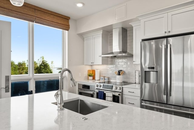 130 Broad Reach Unit 409, Weymouth, MA 02191 - kitchen with appliances with stainless steel finishes, wall chimney range hood, a sink, tasteful backsplash, and plenty of natural light