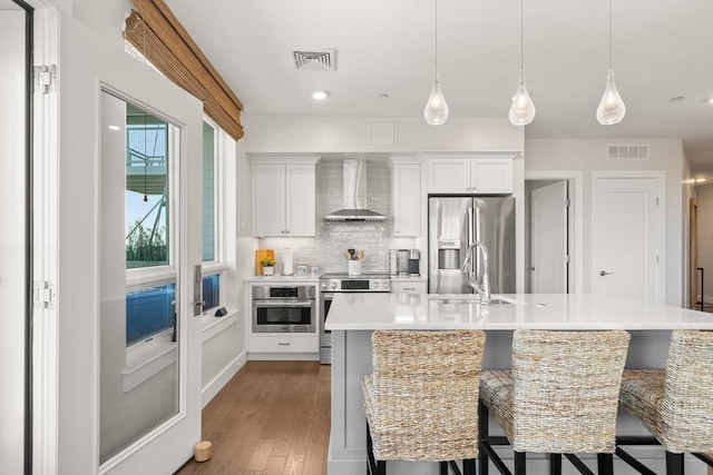 130 Broad Reach Unit 409, Weymouth, MA 02191 - kitchen featuring wall chimney exhaust hood, appliances with stainless steel finishes, a sink, light countertops, and wood finished floors