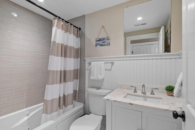 bathroom featuring visible vents, wainscoting, toilet, shower / bath combination with curtain, and vanity