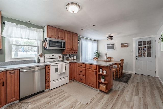 kitchen featuring a wall mounted AC, stainless steel appliances, kitchen peninsula, and light wood-type flooring