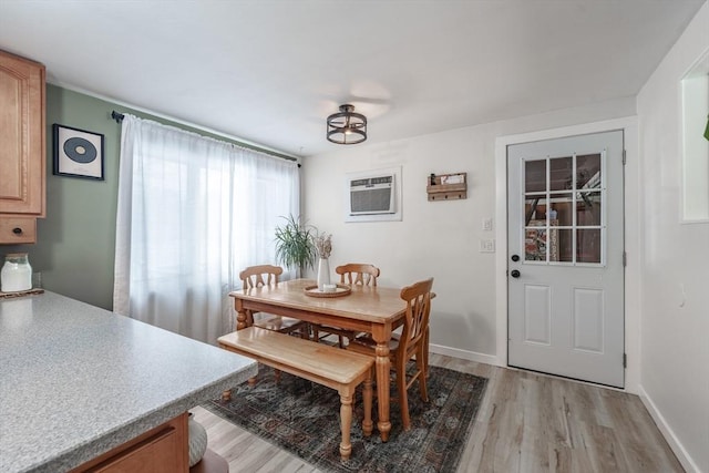 dining space featuring wood-type flooring and an AC wall unit