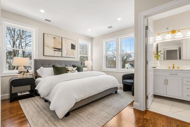 bedroom featuring ensuite bathroom, dark hardwood / wood-style flooring, and sink