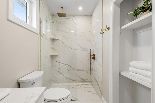 bathroom with tiled shower, vanity, and toilet