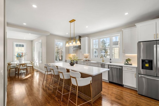 kitchen featuring white cabinetry, decorative light fixtures, stainless steel appliances, and a center island