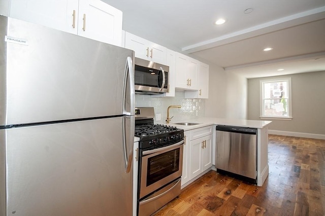 89 Morris St, Boston, MA 02128 - kitchen featuring appliances with stainless steel finishes, dark wood-style floors, a peninsula, white cabinets, and backsplash