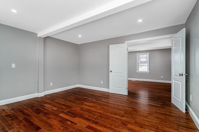 empty room featuring dark hardwood / wood-style flooring and beamed ceiling